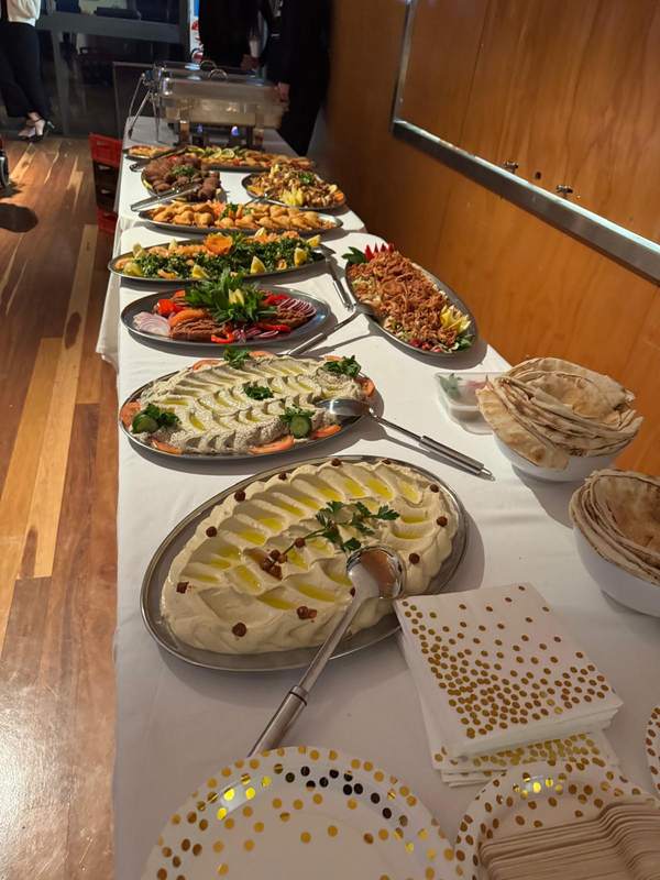 Hommous and baba ghannouj platters, tabouleh, fattoush and finger food on a long buffet table
