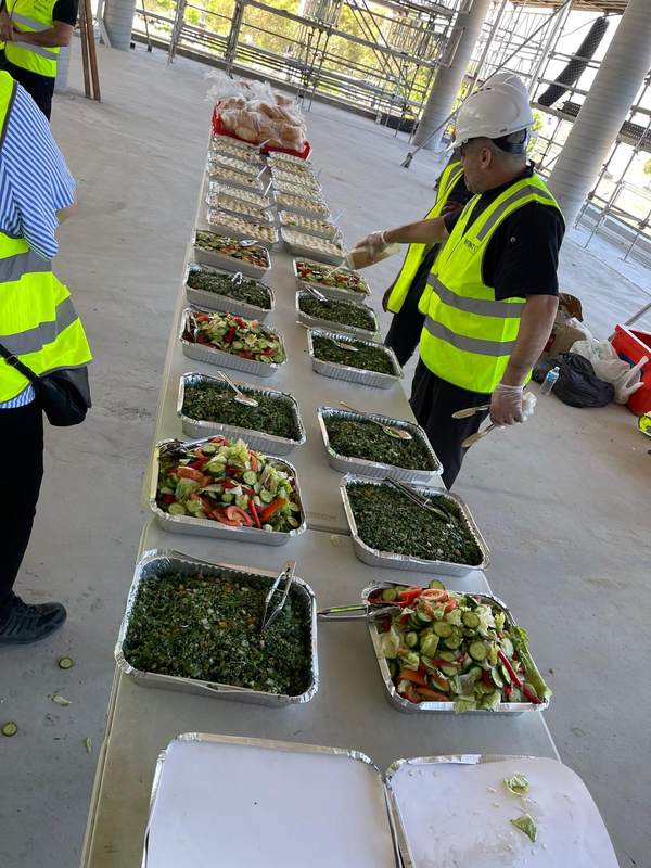 Trays of tabouleh, garden salad and dips set out for a lunch on a building site