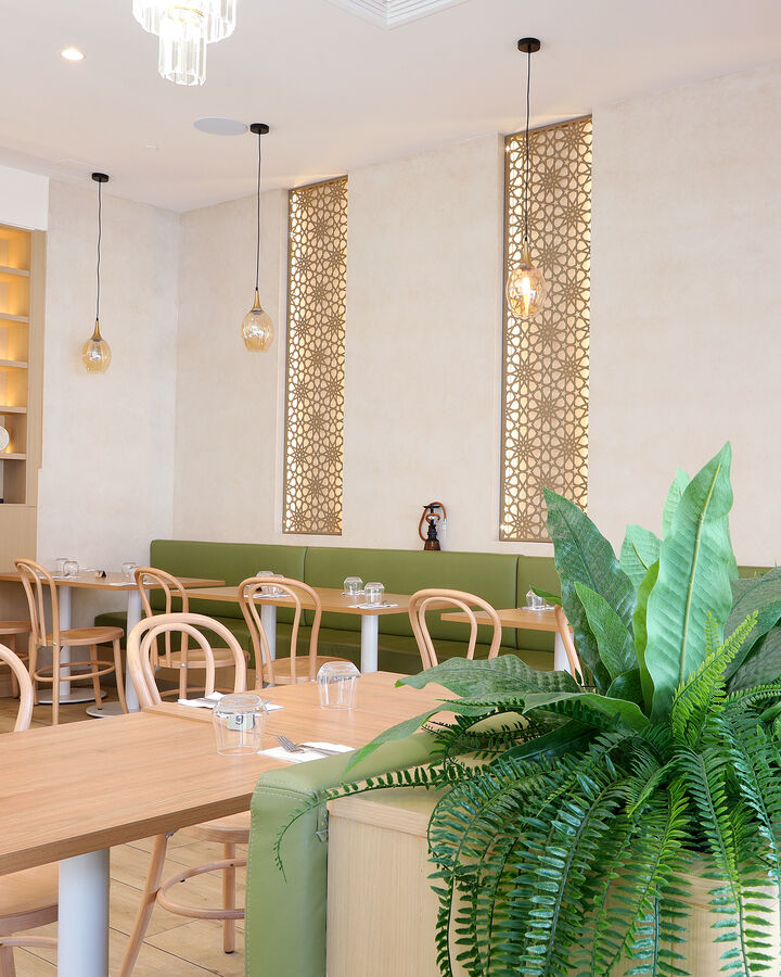 Sage green banquette under carved screens and pendant lights
