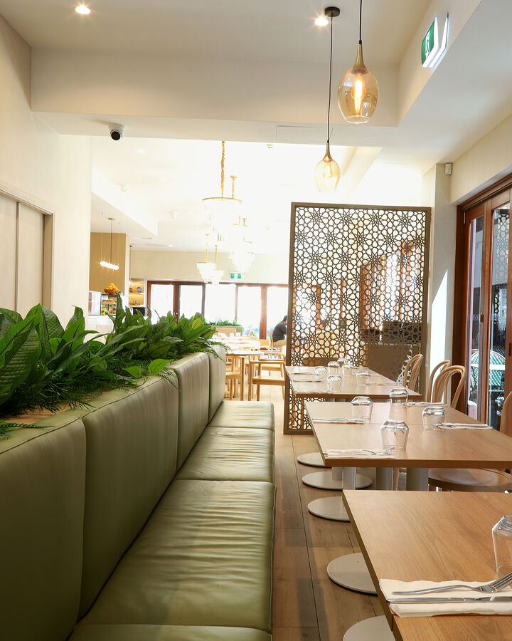 A long green banquette beside the tall timber windows