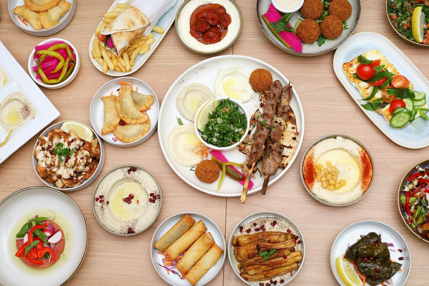 A table of Lebanese mezze: hommous, falafel, kafta skewers, halloumi salad and vine leaves
