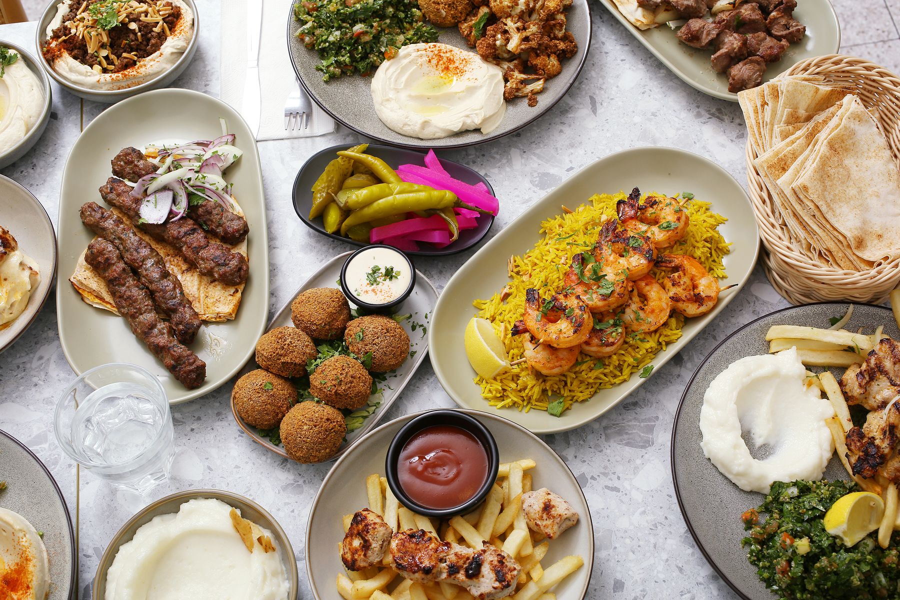 A table of Jasmin 1 dishes ready to share: kafta, falafel, prawns on rice, dips and grills