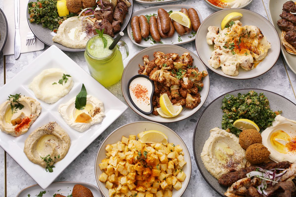 A table set with dips, falafel, sujuk, fried cauliflower, batata harra and mixed grill